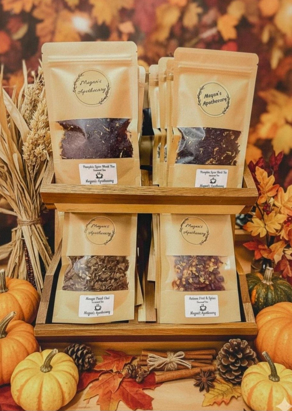 Four pouches of autumn tea on a wooden riser, with pumpkins, cinnamon and autumn leaves